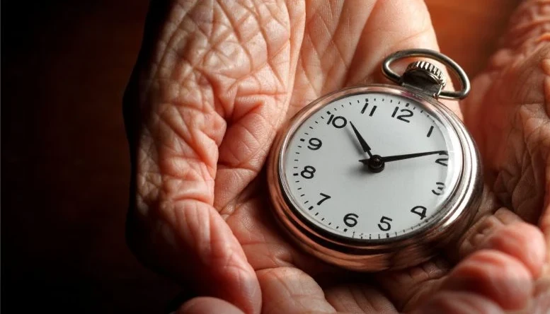 old hands holding a pocket watch