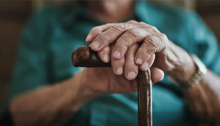 old man's hands resting on cane